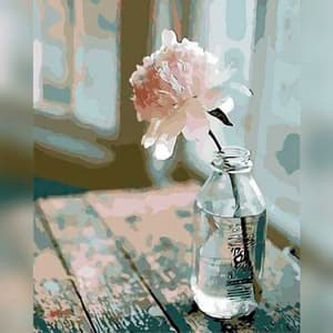 Small bottle with a pink flower on a wooden surface