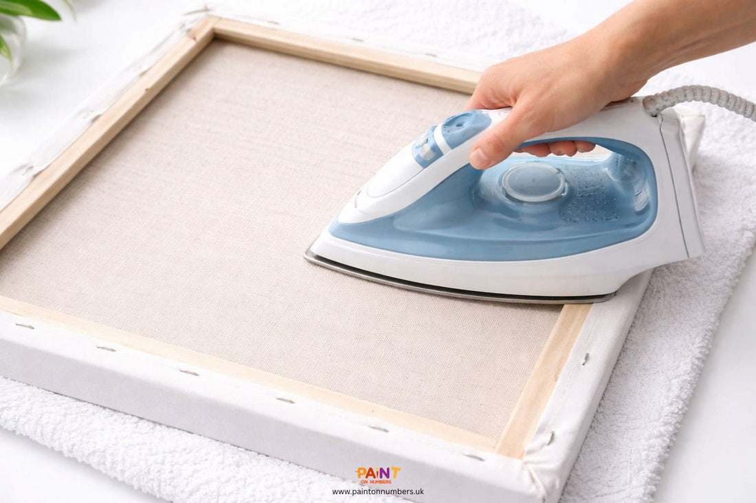 A person carefully ironing the back of a linen paint by numbers canvas to remove creases.