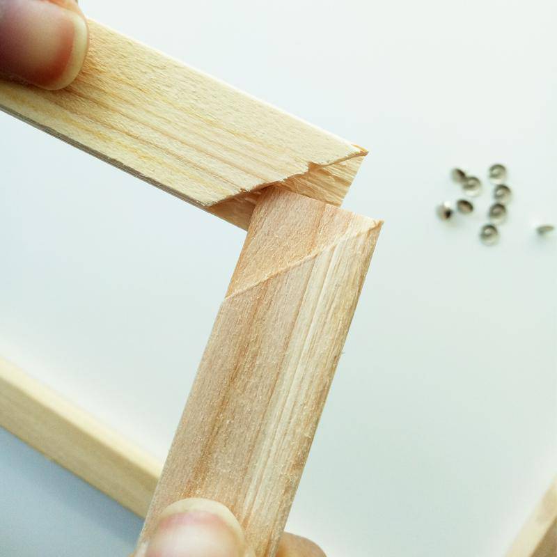 Close-up of wooden stretcher bars being joined together to assemble a DIY canvas frame
