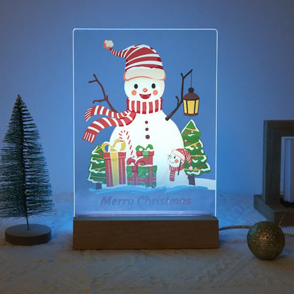 A rectangular acrylic LED night light featuring a festive Christmas snowman design, shown illuminated on a wooden base in a styled holiday setting.