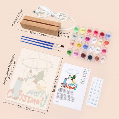 Merry Christmas canvas painting kit with a wooden electric heater, 16 colorful paint pots, two blue paintbrushes, an acrylic sheet with a snowman design, a color chart, and a number grid on a light beige background with dimension annotations.