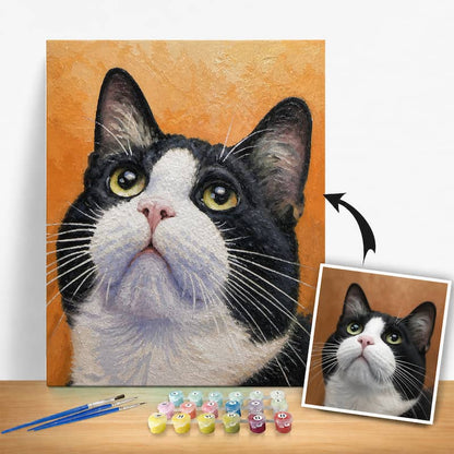 Detailed painting of a black and white cat with a smaller inset photo, surrounded by art supplies on a wooden surface.