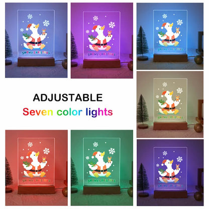 A collage showing a clear acrylic LED night light with a Christmas goose illustration, displayed in seven different adjustable colors: blue, purple, light blue, warm white, red, green, and dark blue. The center of the image features the text 'ADJUSTABLE Seven color lights'.
