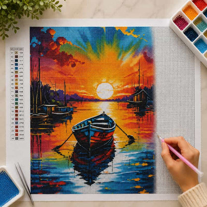 Diamond painting kit with a sunset over water scene, hand holding a tool, and color chart.