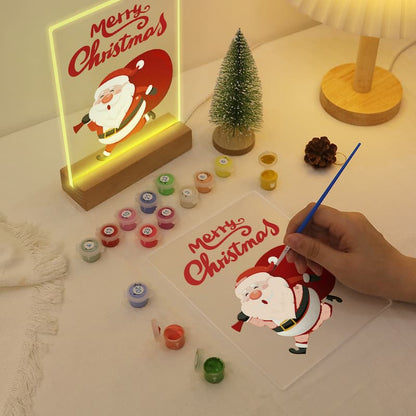 Hand painting a Christmas-themed picture with a lit 'Merry Christmas' sign in the background.