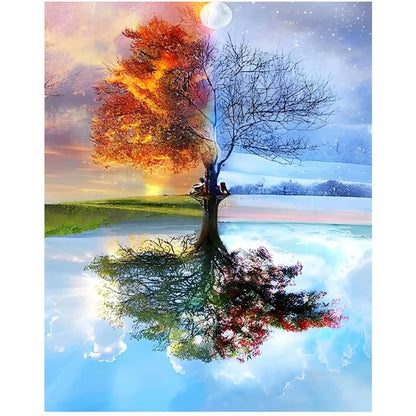 Tree with colorful foliage reflected in water, with a person sitting under it.