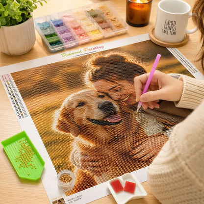 Person working on a diamond painting of a woman and dog with art supplies on a table.
