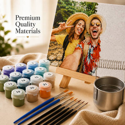 Painting supplies including jars of paint, brushes, and a metal cup on a table with a photo of two people in the background.