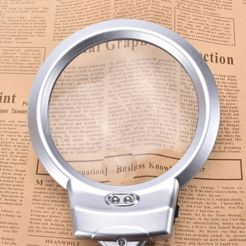Silver magnifying glass on a newspaper background