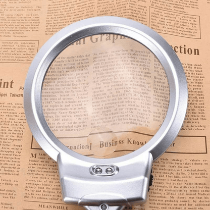 Silver magnifying glass on a newspaper background