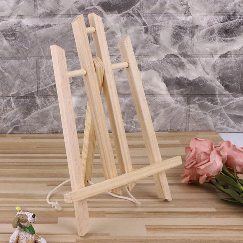 Small wooden easel on a marble surface with flowers and a toy dog.